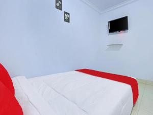 um quarto com uma cama branca e uma televisão na parede em Tiny House Gianyar em Gianyar