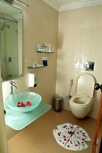 a bathroom with a sink and a toilet and a mirror at Gokulam Park in Cochin