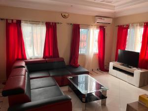 a living room with a couch and red curtains at B&Y Holiday Apartments in Brusubi