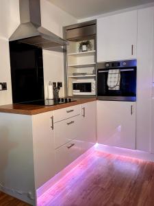 eine Küche mit weißen Schränken und LED-Beleuchtung in der Unterkunft Salford Quays Apartment, Manchester in Manchester