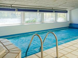 a large swimming pool with blue water and windows at 14 person holiday home in Nex in Snogebæk