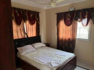 um quarto com uma cama e duas janelas com cortinas em B&Y Holiday Apartments em Brusubi