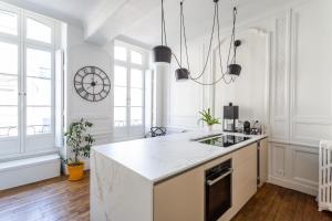 biała kuchnia ze zlewem i zegarem na ścianie w obiekcie Appartement design au coeur de Rennes w mieście Rennes +10 zdjęć