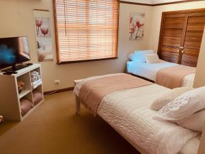 a bedroom with two beds and a flat screen tv at Paradise Lodge - Blue Mountains Wonderland in Linden