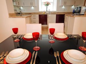 a table with red plates and wine glasses on it at Riviera Apartment in Torquay