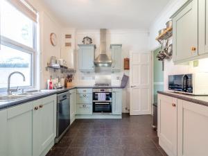 a kitchen with white cabinets and a sink at Hill House in Sholden