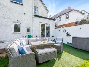 a patio with a couch and a table and chairs at Hill House in Sholden