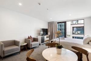 um quarto de hotel com uma cama, uma mesa e cadeiras em FERNZ Motel & Apartments Birkenhead em Auckland