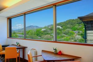 a room with a large window with a table and chairs at ホテル長楽館 京都 祇園 in Kyoto