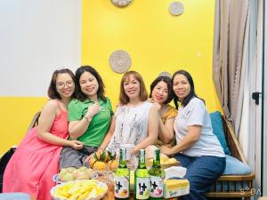 eine Gruppe von Frauen, die mit Getränken auf einer Bank sitzen in der Unterkunft Mon Sapphire Homestay * View Sea and Poem Mountain in Hạ Long