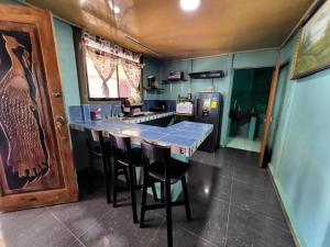a kitchen with a bar with chairs and a refrigerator at Casa Mar y Arena in Golfito