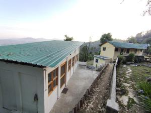 een wit huis met een groen dak en een tuin bij Himalaya View in Rānīkhet