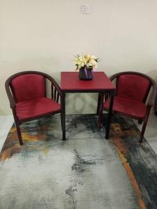 two chairs and a red table with flowers on it at Homestay CikguRose UMK in Bachok