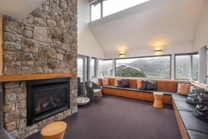 sala de estar con chimenea y pared de piedra en Kooloora Lodge en Perisher Valley