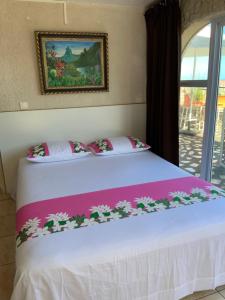 Tahitininalodge 1 في فا: غرفة نوم بها سرير أبيض وعليه زهور