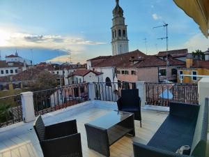 Un balcón con sillas, una mesa y una torre de reloj. en VENICE HOLIDAY TERRACE en Venecia
