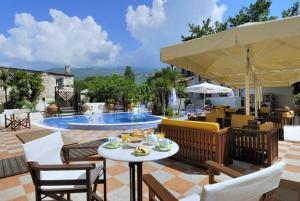 een patio met een tafel en stoelen en een zwembad bij Enalion Hotel in Kala Nera
