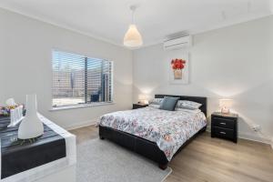a white bedroom with a bed and a window at Cadell Street Apartments Goolwa in Goolwa
