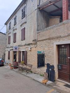 an old brick building with a bench in front of it at Sobe Anja in Brtonigla