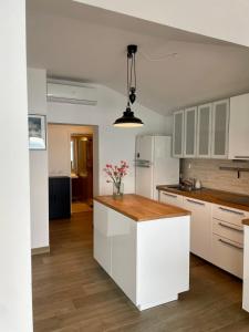 a kitchen with white cabinets and a wooden counter top at Seafront Apartment Strunjan in Strunjan