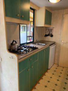 a kitchen with green cabinets and a stove top oven at Comfortabele familie chalets met veranda incl airco dichtbij zee! in Viareggio