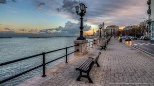 a row of benches on a sidewalk next to the water at Casa Lucia in Bari