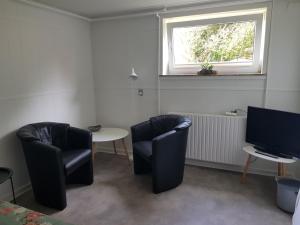 a room with two chairs and a table and a television at Feriehuse Hvide Sande in Hvide Sande