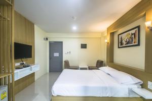 a hotel room with a bed and a flat screen tv at Petchsiri Room เพชรสิริรูม in Ban Chuat Plai Mai