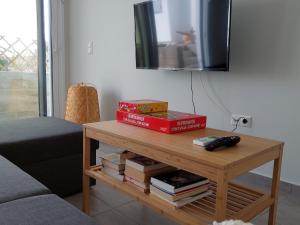 ein Wohnzimmer mit einem Tisch mit Büchern und einem TV in der Unterkunft Bahia- apartment by the sea,close to cedar forest! in Elafonisos