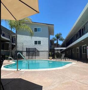 a swimming pool in front of a building with an umbrella at Homey Oasis within minutes of San Diego adventures in San Diego