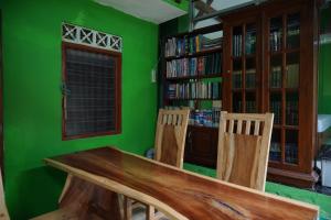 a green room with a wooden table and two chairs at Omah Bogem Homestay Syariah in Randugunting