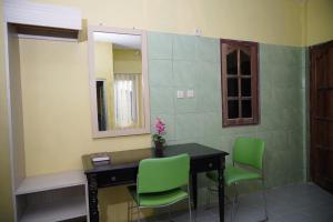 a room with a desk and two green chairs at Omah Bogem Homestay Syariah in Randugunting