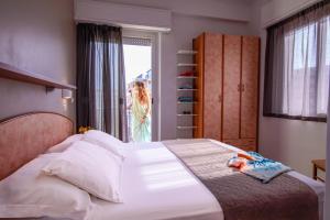 una camera con un letto e una donna che guarda fuori dalla finestra di Hotel Holland a Rimini