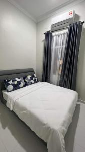 ein Bett mit Kissen und ein Fenster in einem Zimmer in der Unterkunft El Manzil Homestay with Pool in Guar Chempedak