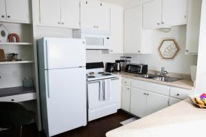 a white kitchen with white cabinets and a white refrigerator at Homey Oasis within minutes of San Diego adventures in San Diego