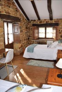 Casa Rural Los Riveros de Jeromo في Selaya: غرفة نوم بسريرين وجدار من الطوب