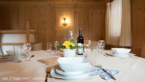 einen Tisch mit Tellern und Gläsern sowie eine Flasche Wein in der Unterkunft Landhaus & Schloss Anras in Anras