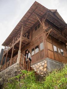 une femme debout sur un balcon d'une maison dans l'établissement Villa Watu kodok - Villa Located Close to The Beach, à Baron