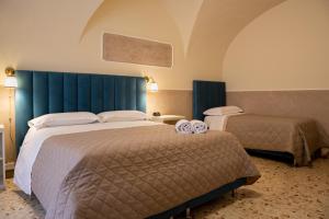 une chambre d'hôtel avec deux lits et une tête de lit bleue dans l'établissement Il Gattopardo House, à Catane