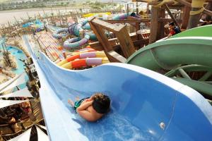 a child laying in a water slide at a water park at Top Rated Family Suite - Yas in Abu Dhabi
