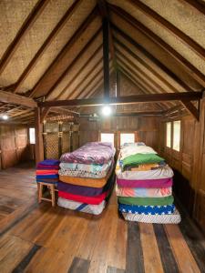 two beds in a room with wooden floors at Villa Watu kodok - Villa Located Close to The Beach in Baron