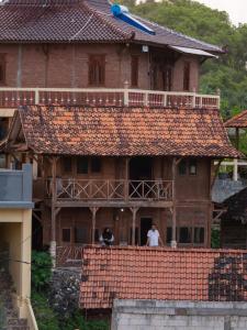two people standing on the balcony of a house at Villa Watu kodok - Villa Located Close to The Beach in Baron