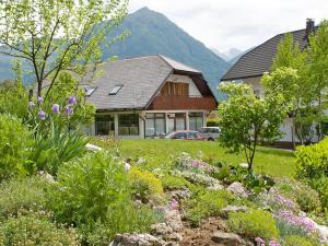 a garden in front of a house with mountains at Apartments and Rooms Tajcr in Bovec