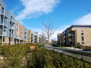 a bench sitting in the grass next to some buildings at Townhouse in Ebbsfleet sleeps 9 with free parking in Greenhithe