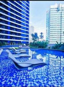 a swimming pool with lounge chairs in a city at Air Residences Condominium Deluxe in Manila