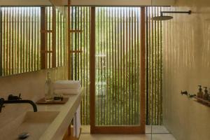 uma casa de banho com um lavatório e um chuveiro com uma janela em Innit Lombok em Ekas