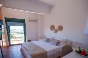 a white bedroom with a bed and a balcony at Villa Calliope Lardos in Lartos