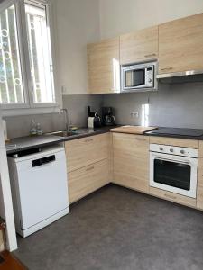 a kitchen with wooden cabinets and a white dishwasher at Duplex 130m2 dans un mas entouré de vergers - piscine in Saint-Féliu-dʼAvall