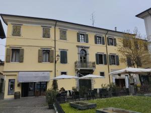 a yellow building with tables and umbrellas in front of it at Domus terme romane in Cividale del Friuli