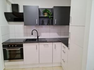 a white kitchen with white cabinets and a sink at Apartman Vinyl - self check-in in Osijek